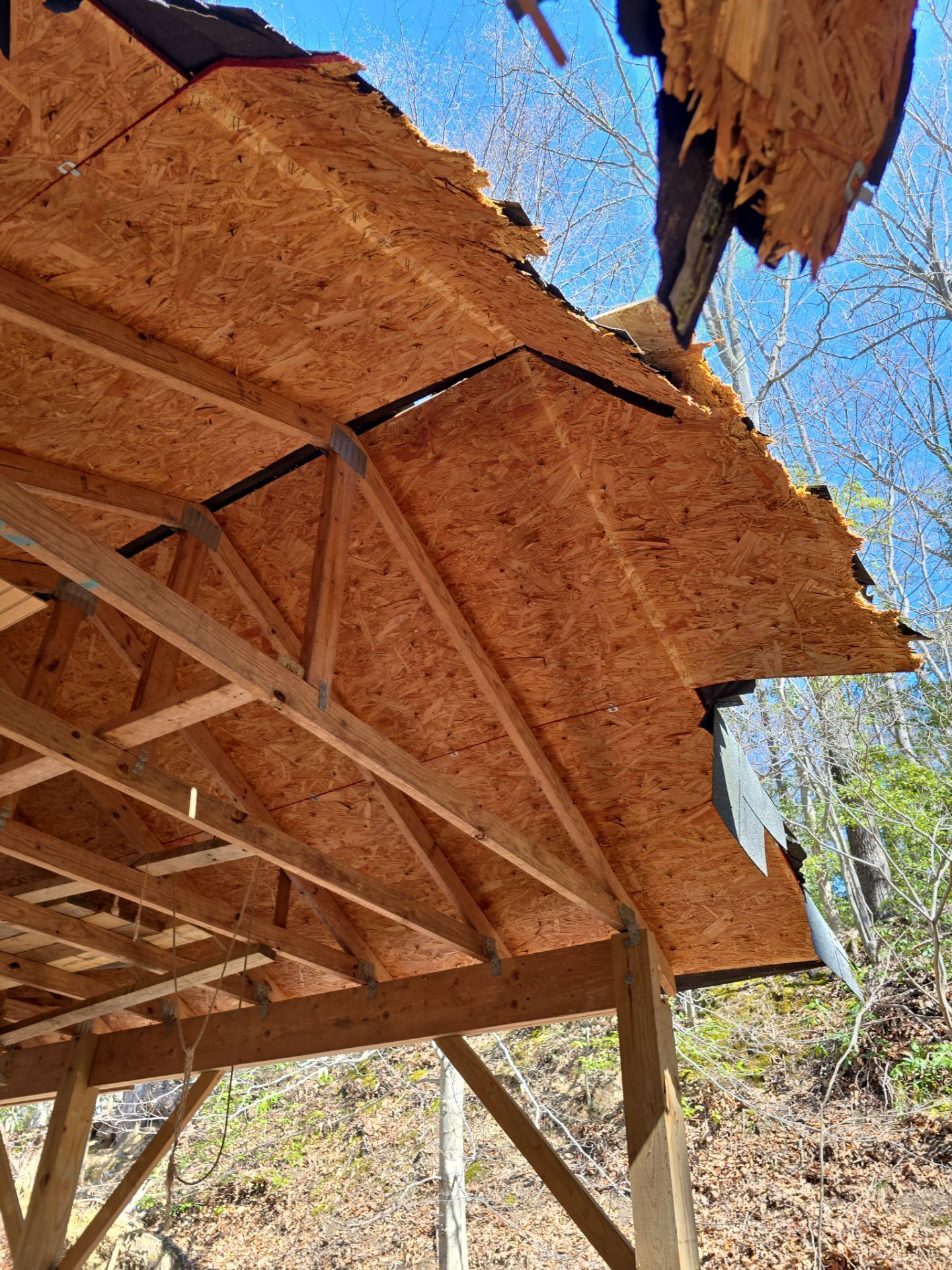 A wooden structure with a roof that has been damaged by a storm.