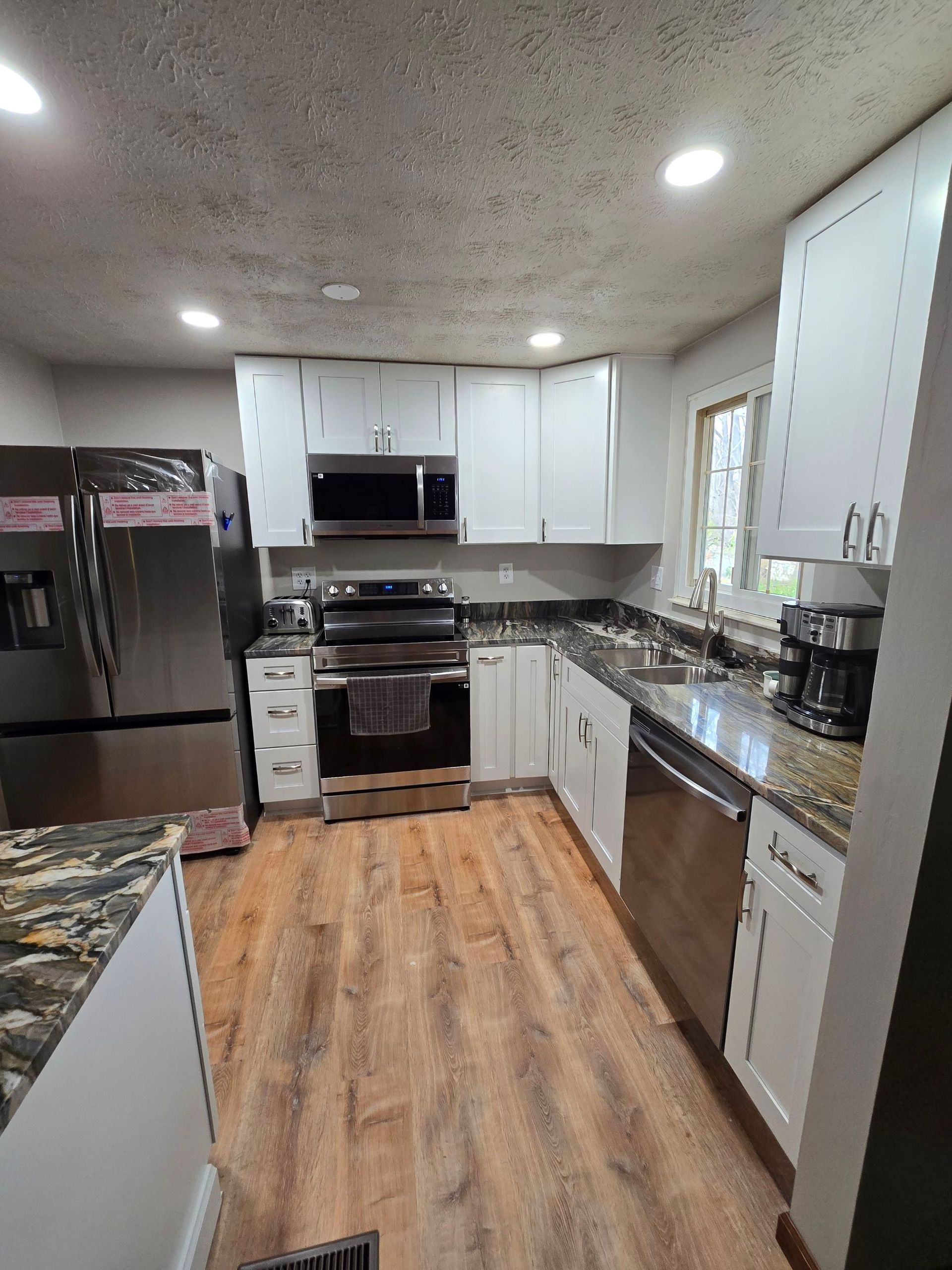A kitchen with white cabinets , stainless steel appliances , and hardwood floors.