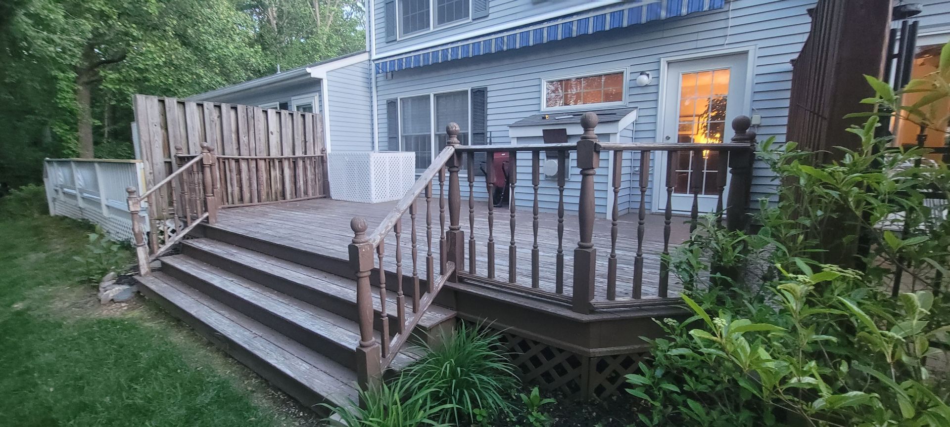 A large deck with stairs leading up to it is in front of a house.