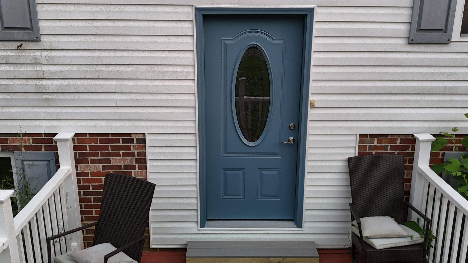 A blue door with a glass window is on the front of a house.