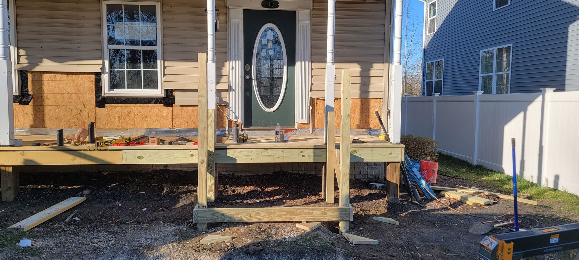 A wooden porch is being built in front of a house.