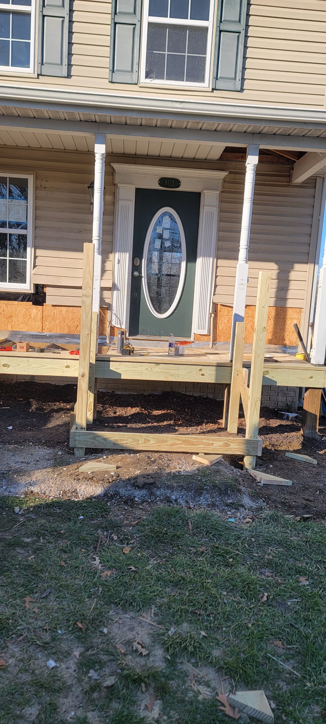 A wooden porch is being built in front of a house.