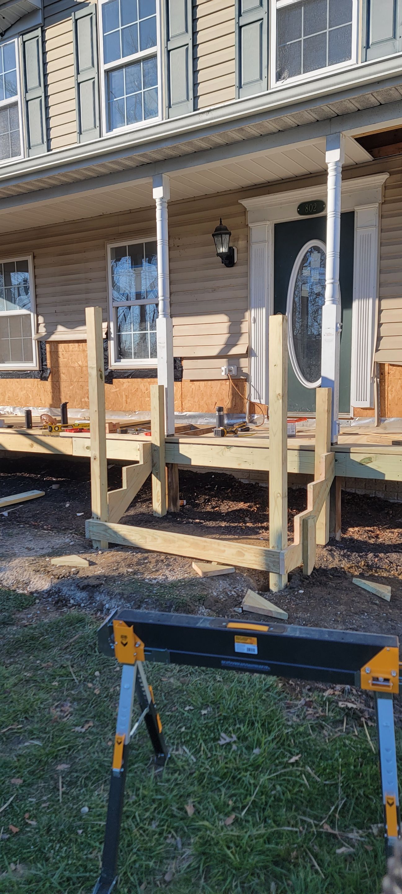 A wooden deck is being built in front of a house.