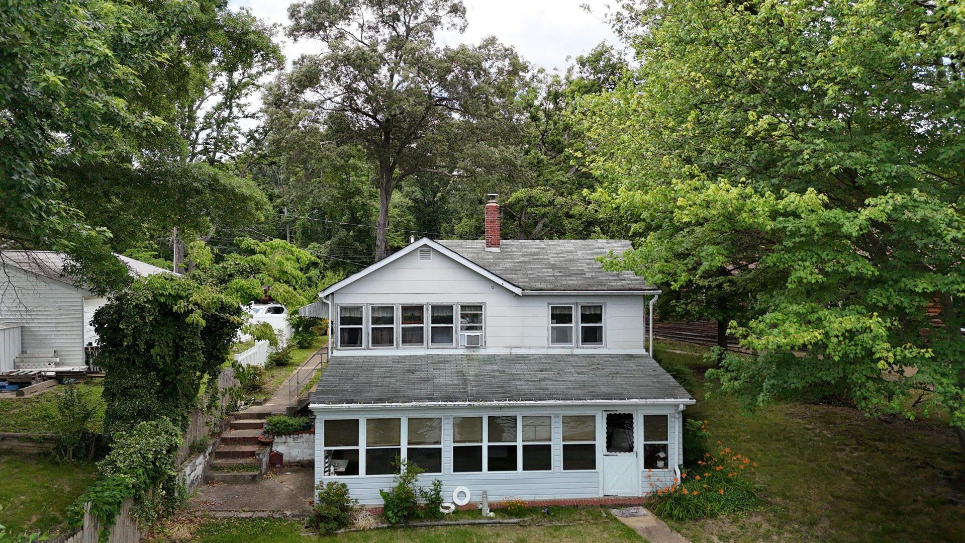 An aerial view of a white house surrounded by trees.