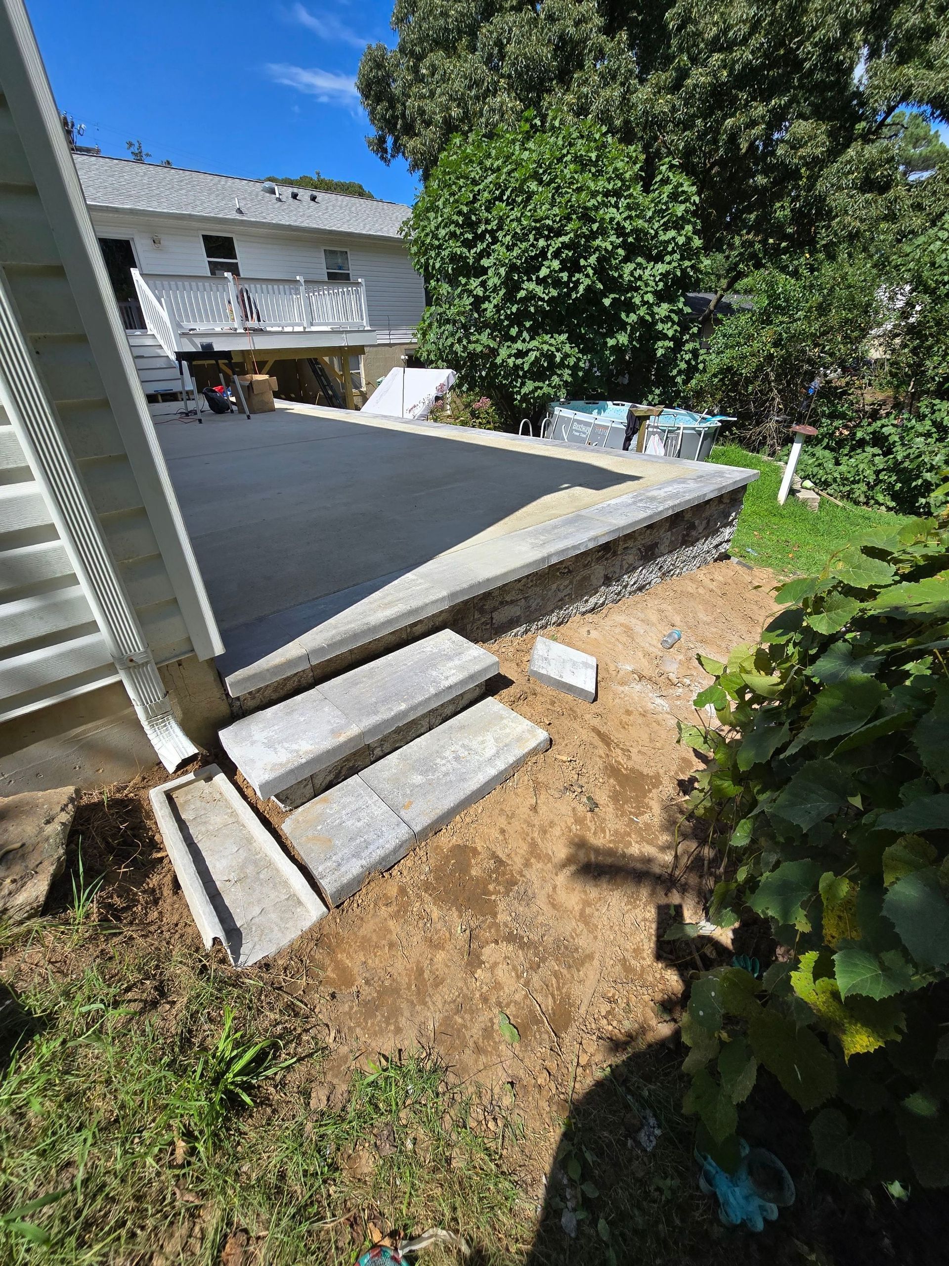 A concrete walkway is being built in the backyard of a house.
