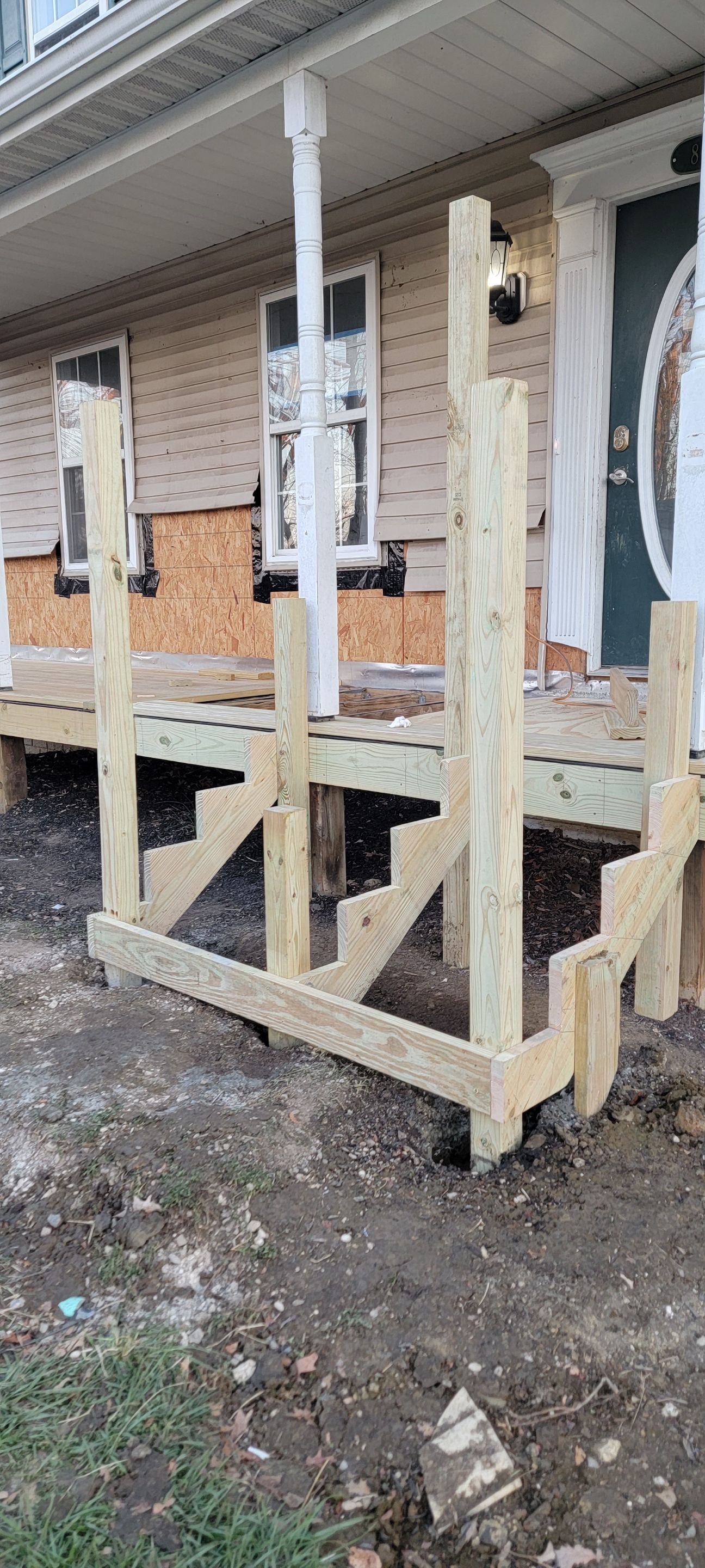 A wooden deck is being built in front of a house.