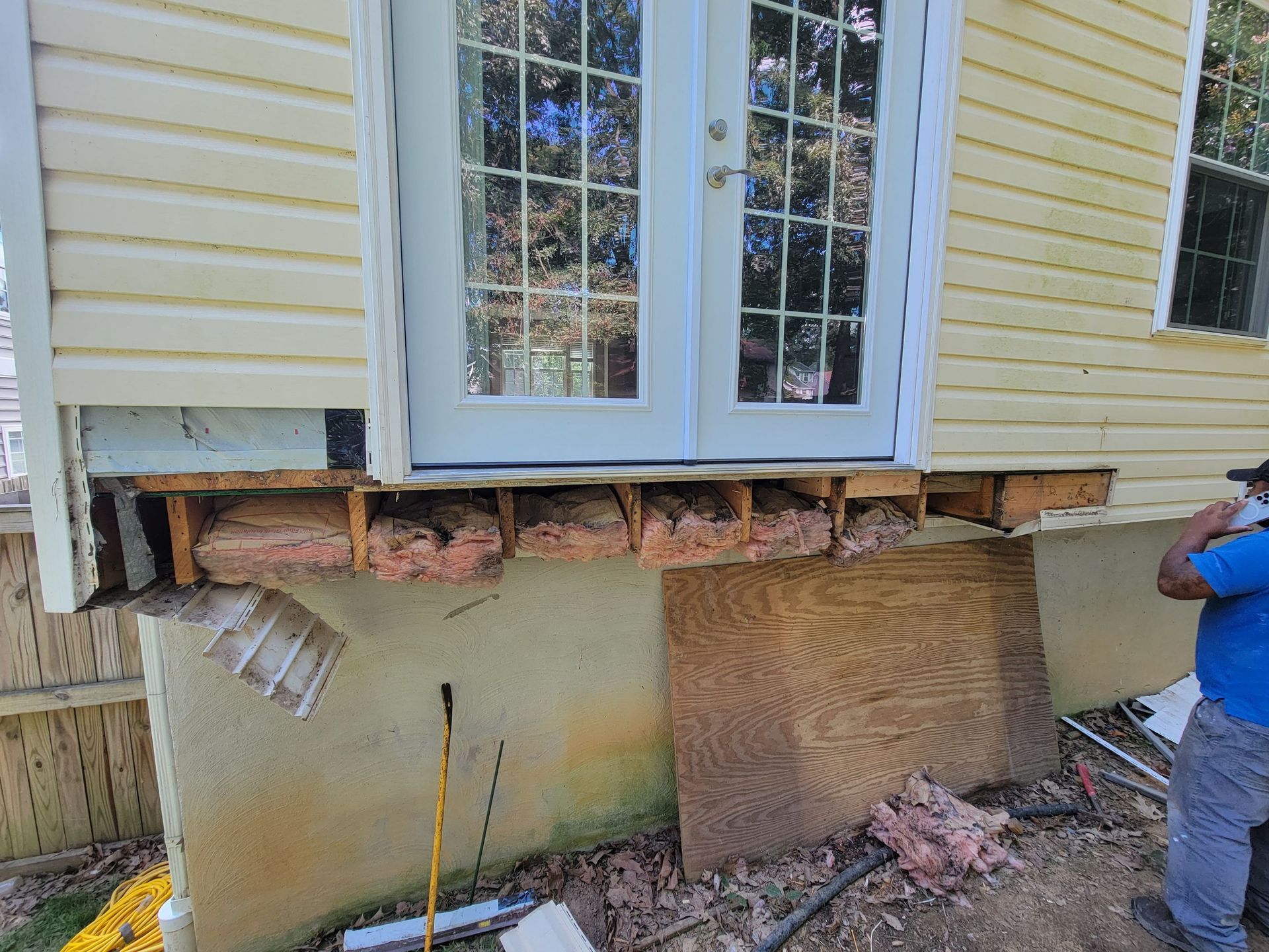 A man is standing in front of a house that is being remodeled.