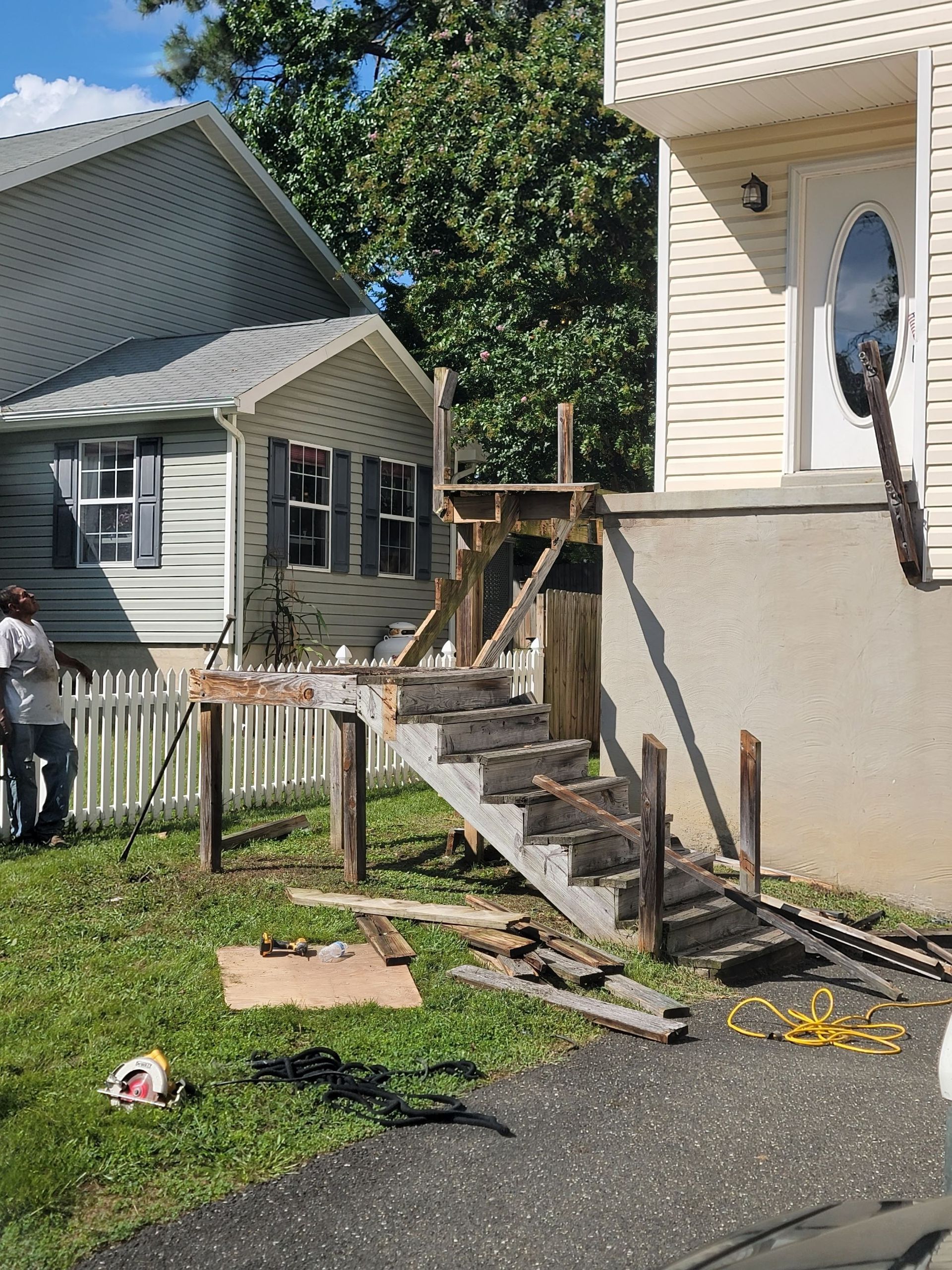A man is standing in front of a house with stairs being built.