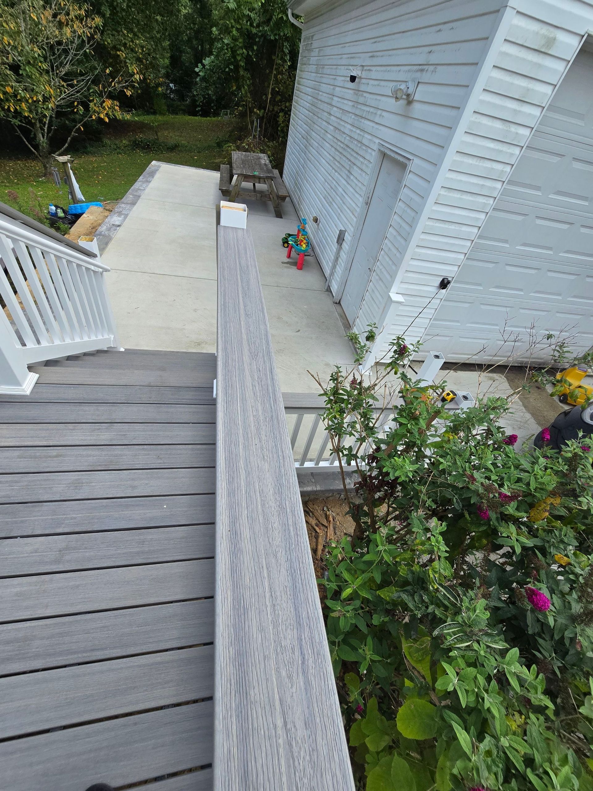 A wooden deck with stairs leading up to a white house.
