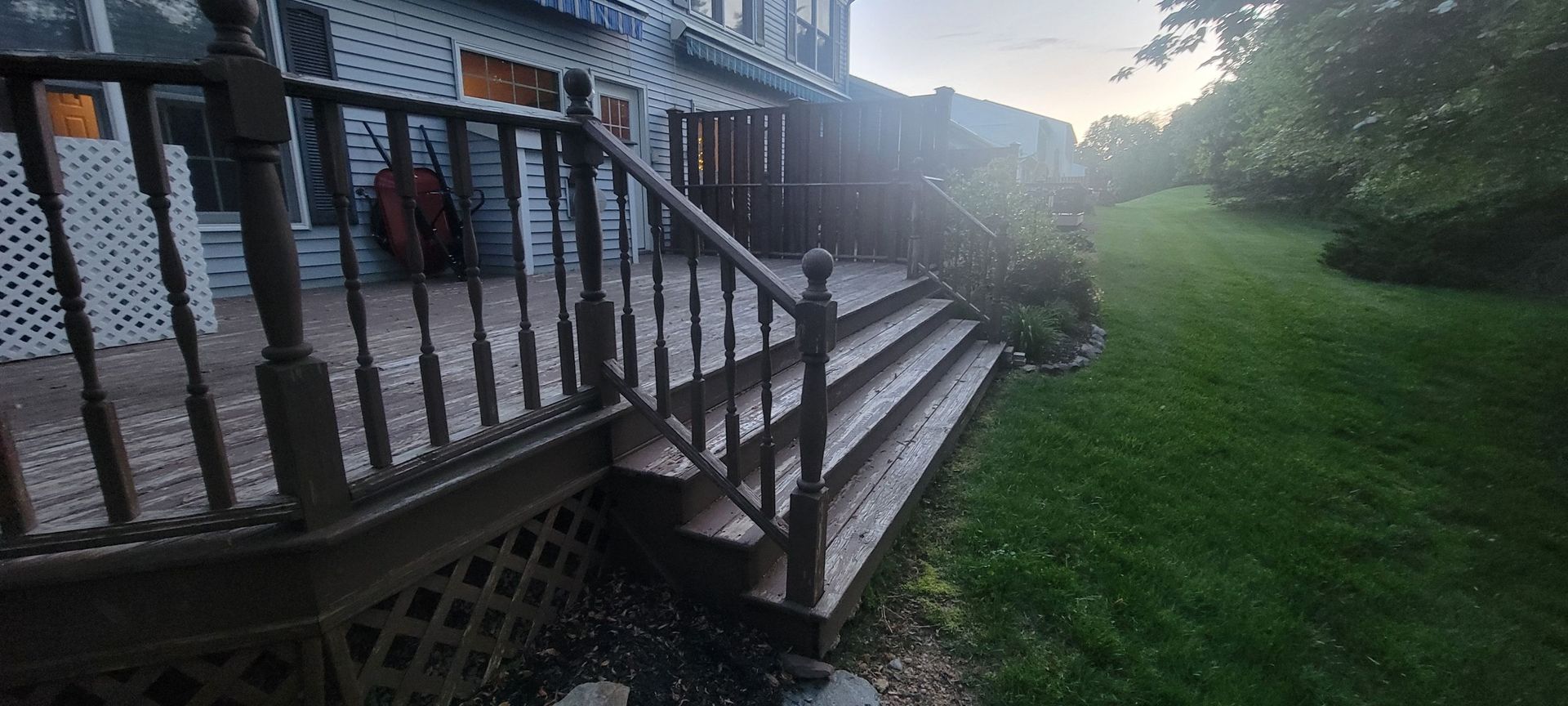 A wooden deck with stairs leading up to it in front of a house.