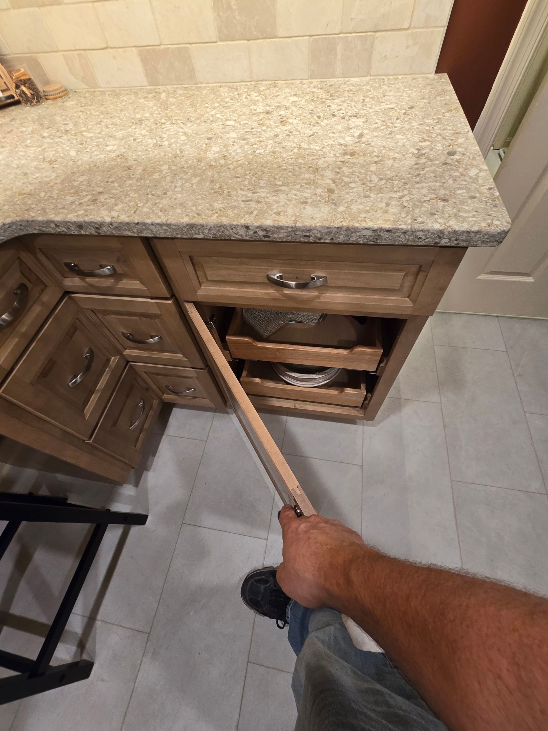 A person is holding a piece of wood in front of a kitchen counter