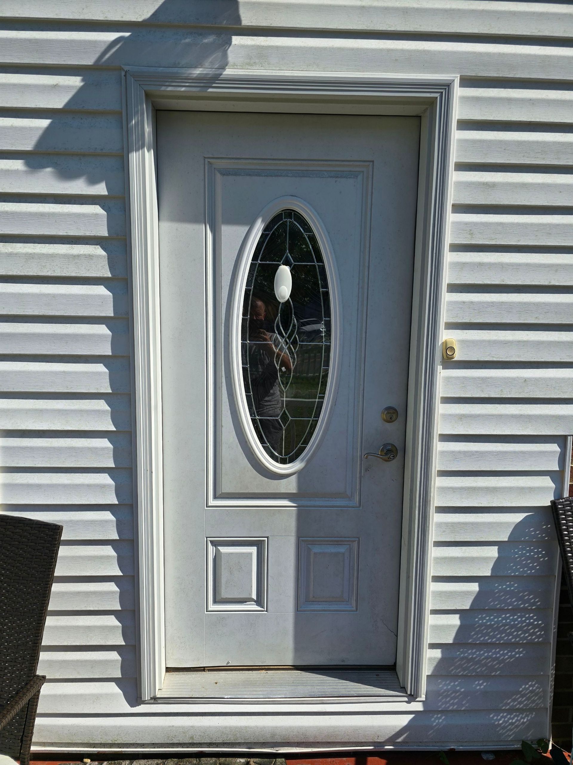 A white door with an oval window on the side of a house