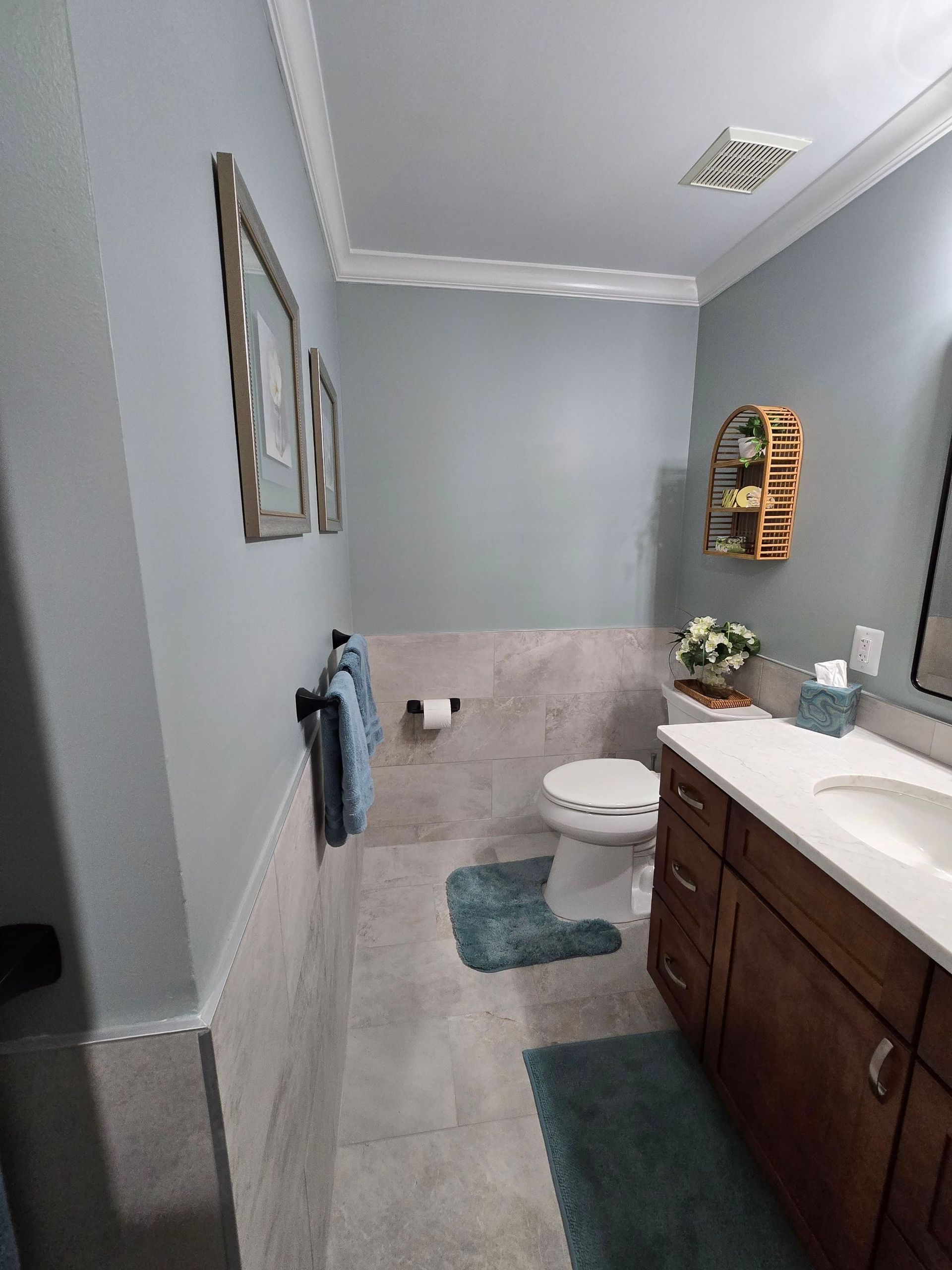 A bathroom with a toilet , sink and mirror.