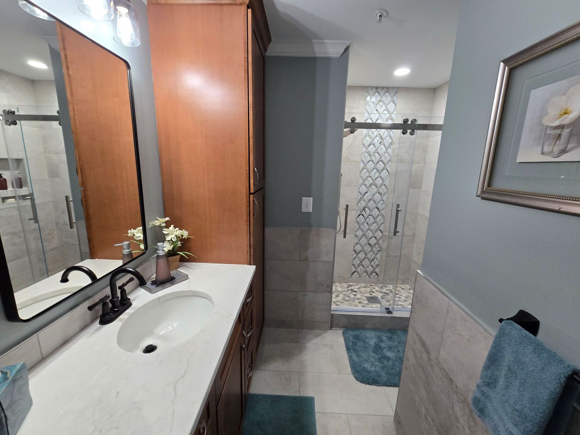 A bathroom with a sink , mirror and shower.
