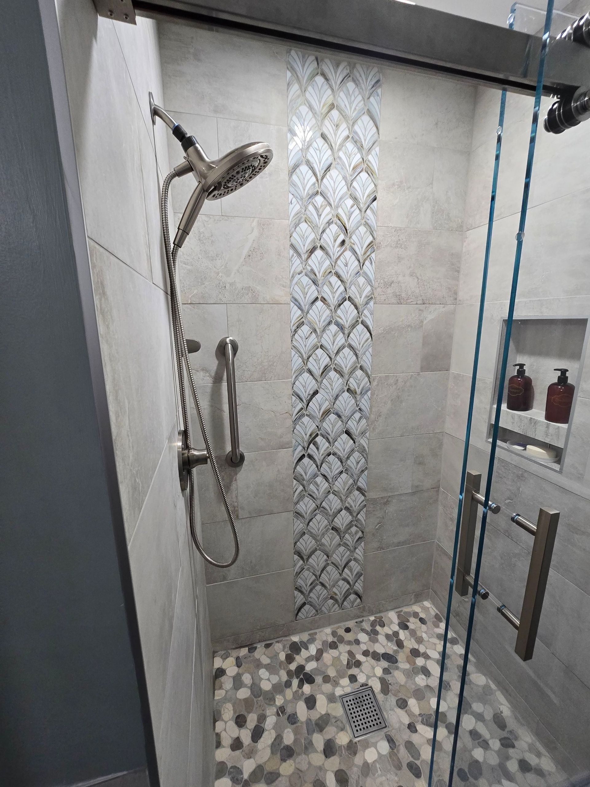 A shower with a sliding glass door and a shower head.