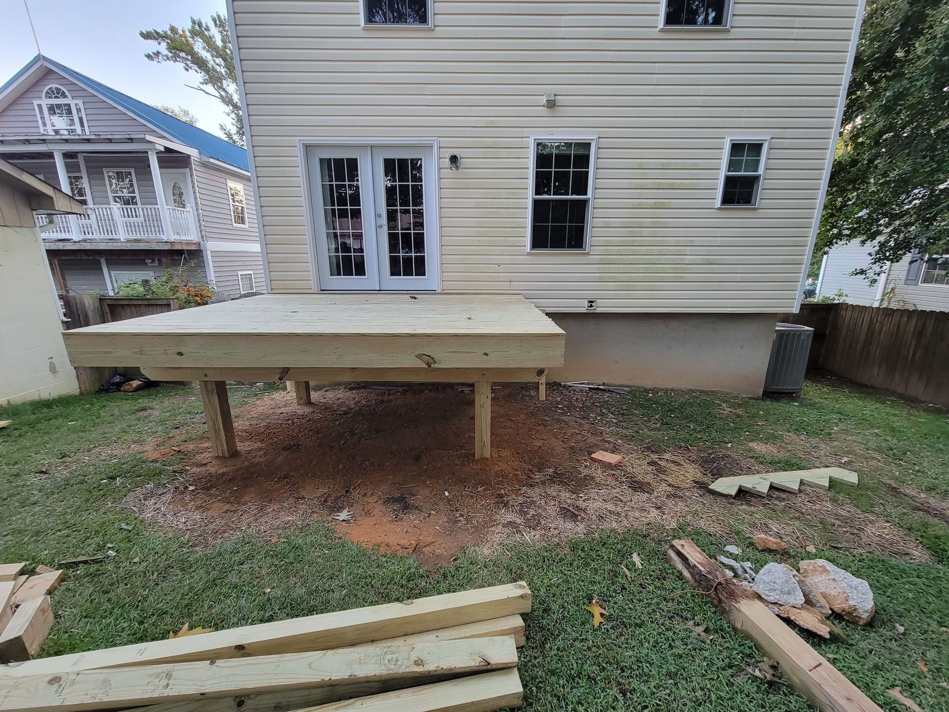 A wooden deck is being built in the backyard of a house.