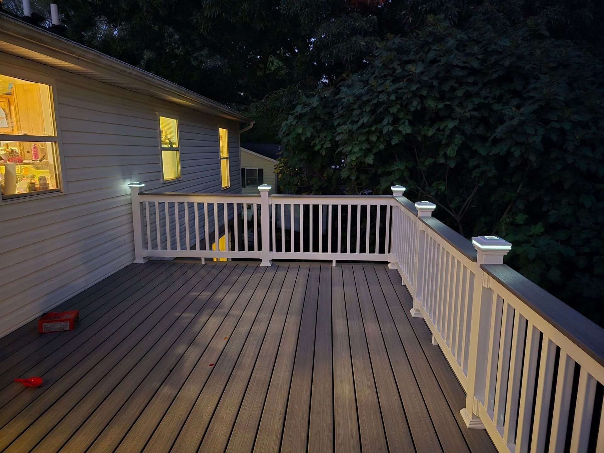 A deck with a white railing is lit up at night.