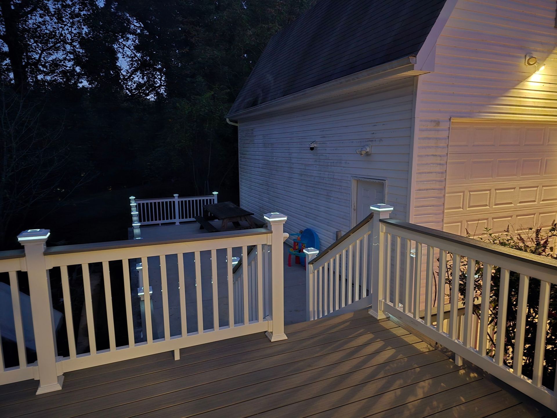 A deck with stairs leading up to a house at night