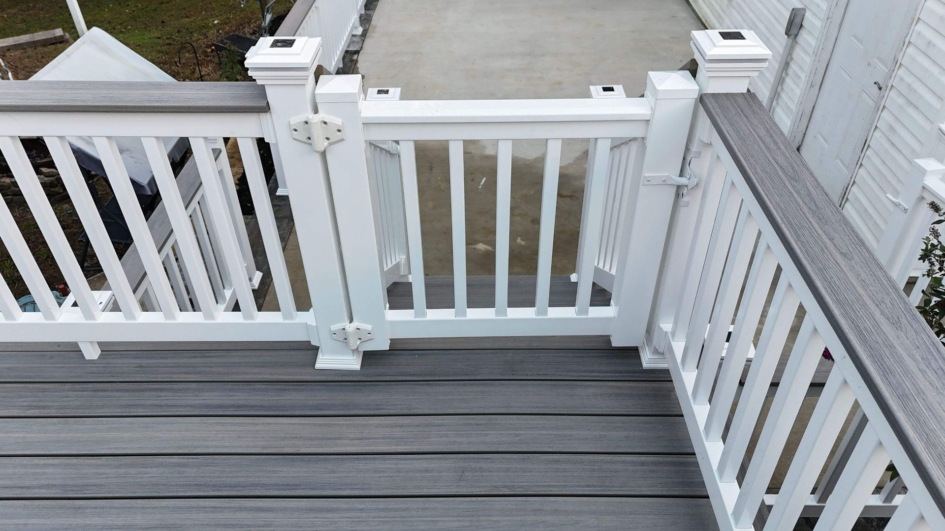 A white railing on a deck with a gray wooden floor