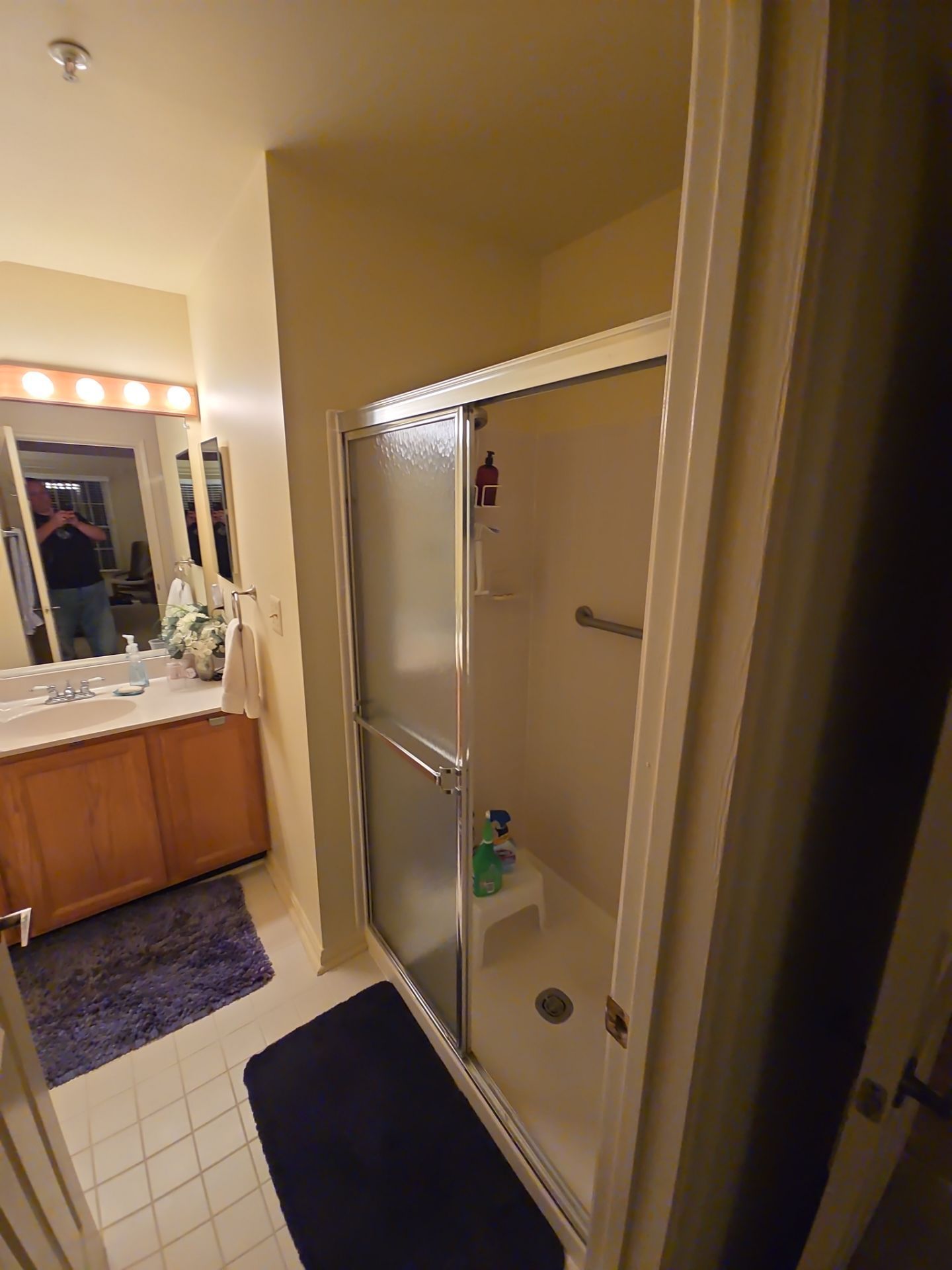 A bathroom with a walk in shower , sink and mirror.