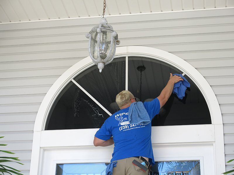 Man Cleaning Arched Windows of Home — Fort Myers, FL — Wipe Out Windows