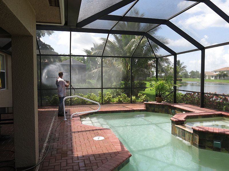 Man Cleaning Lanai Enclosure Using Pressure Washer — Fort Myers, FL — Wipe Out Windows