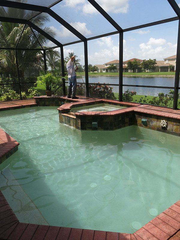 Man Cleaning Pool Pathway Using Pressure Washer — Fort Myers, FL — Wipe Out Windows
