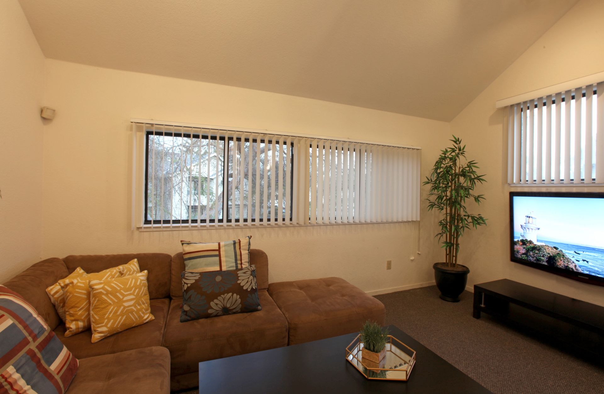 Living room with brown sectional, dark coffee table, and a TV.