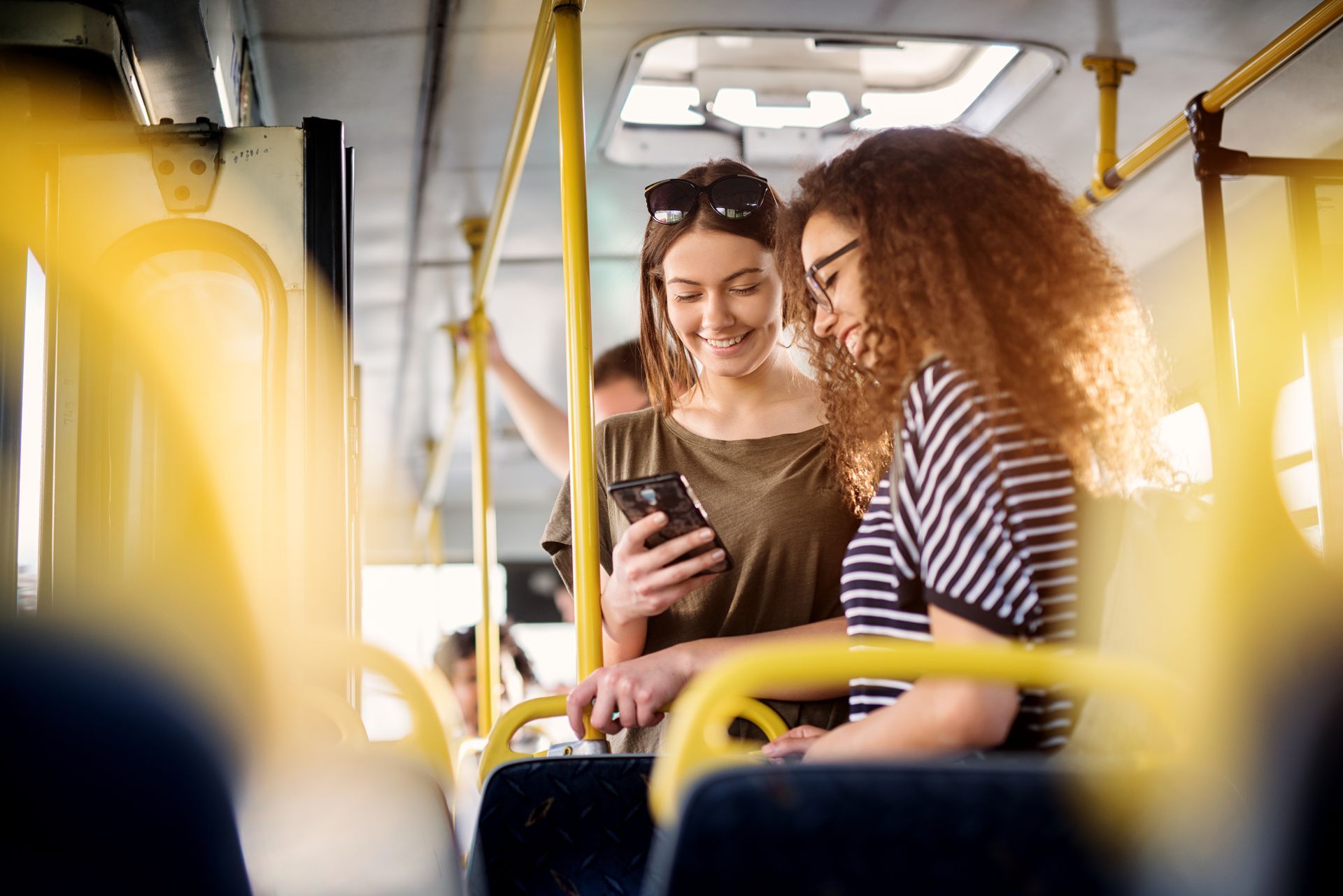 photo of two women looking at a phone while riding a bus
