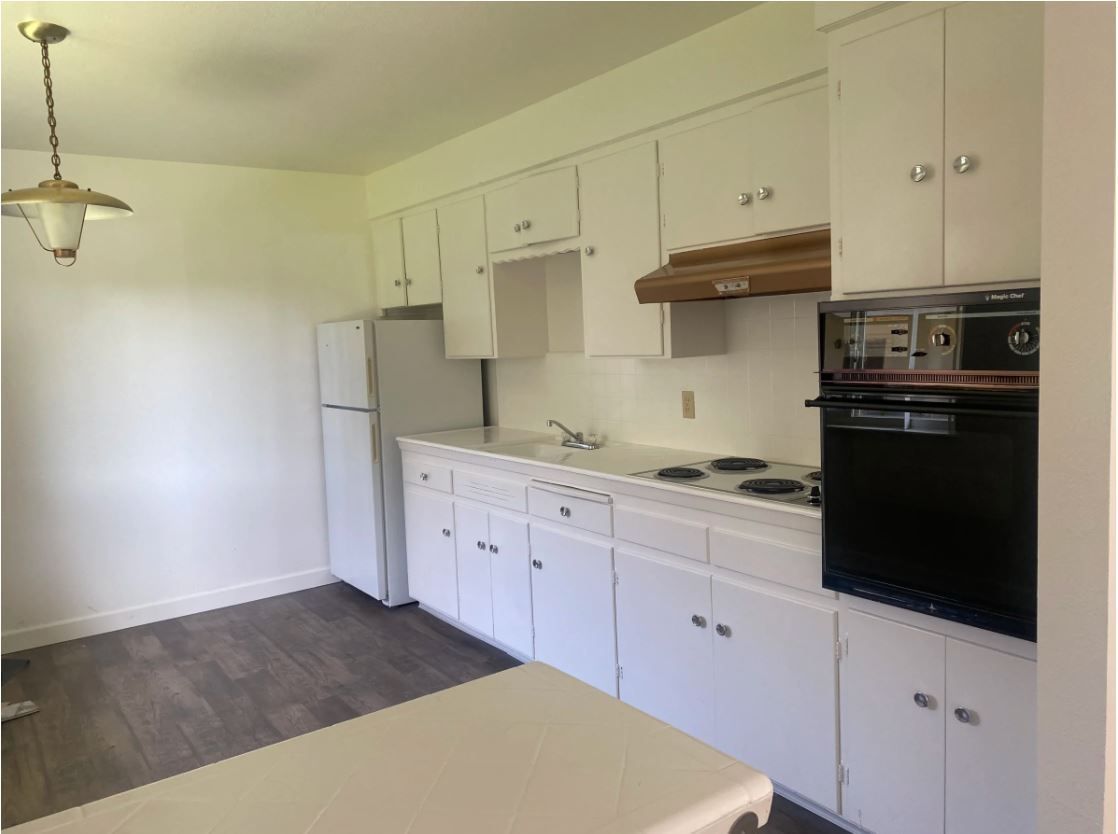 White kitchen with cabinets, appliances, and a countertop.