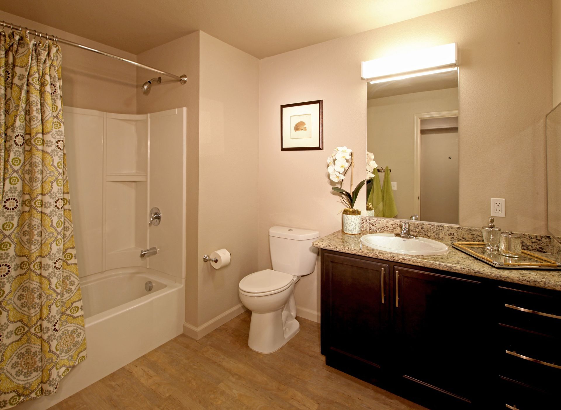Bathroom with shower/tub, toilet, vanity, and mirror. Light brown walls and flooring; dark brown vanity.