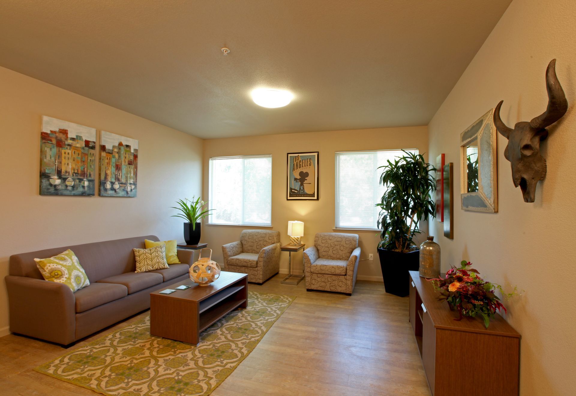Living room with couch, chairs, art, and a cow skull.