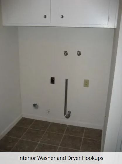 Laundry room with washer and dryer hookups on white wall, cabinets above, and tiled floor.