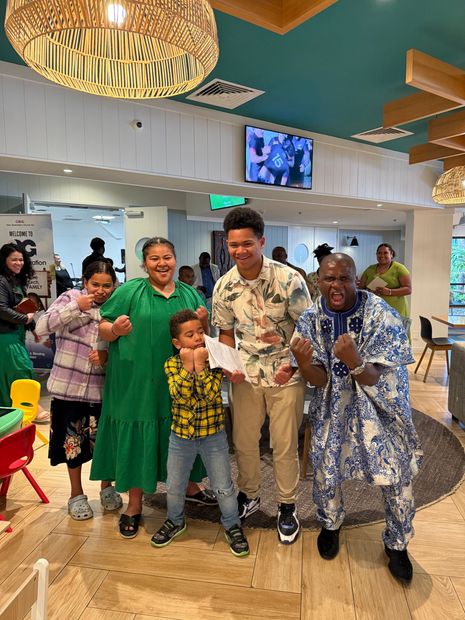 A diverse family celebrates, posing together indoors, cheerful expressions.