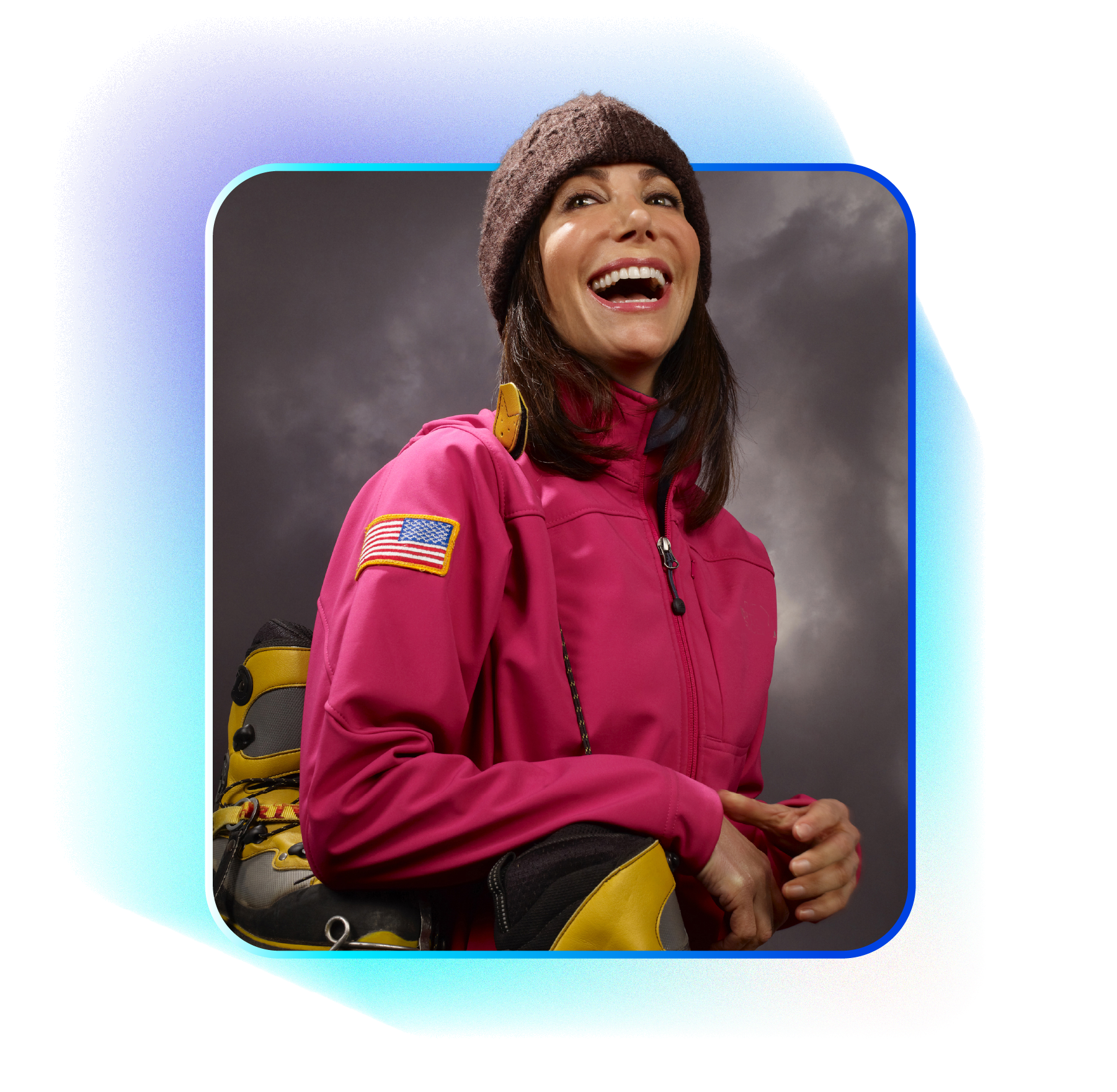 Promotional image for Alison Levine in a pink jacket and hat, laughing, with backpack, American flag patch, gray background.