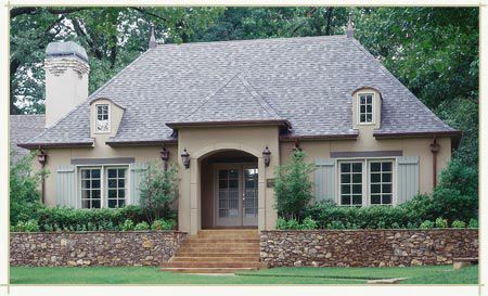 A house with a gray roof and a stone wall