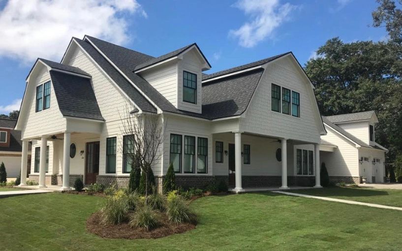 A large white house with a black roof and green windows