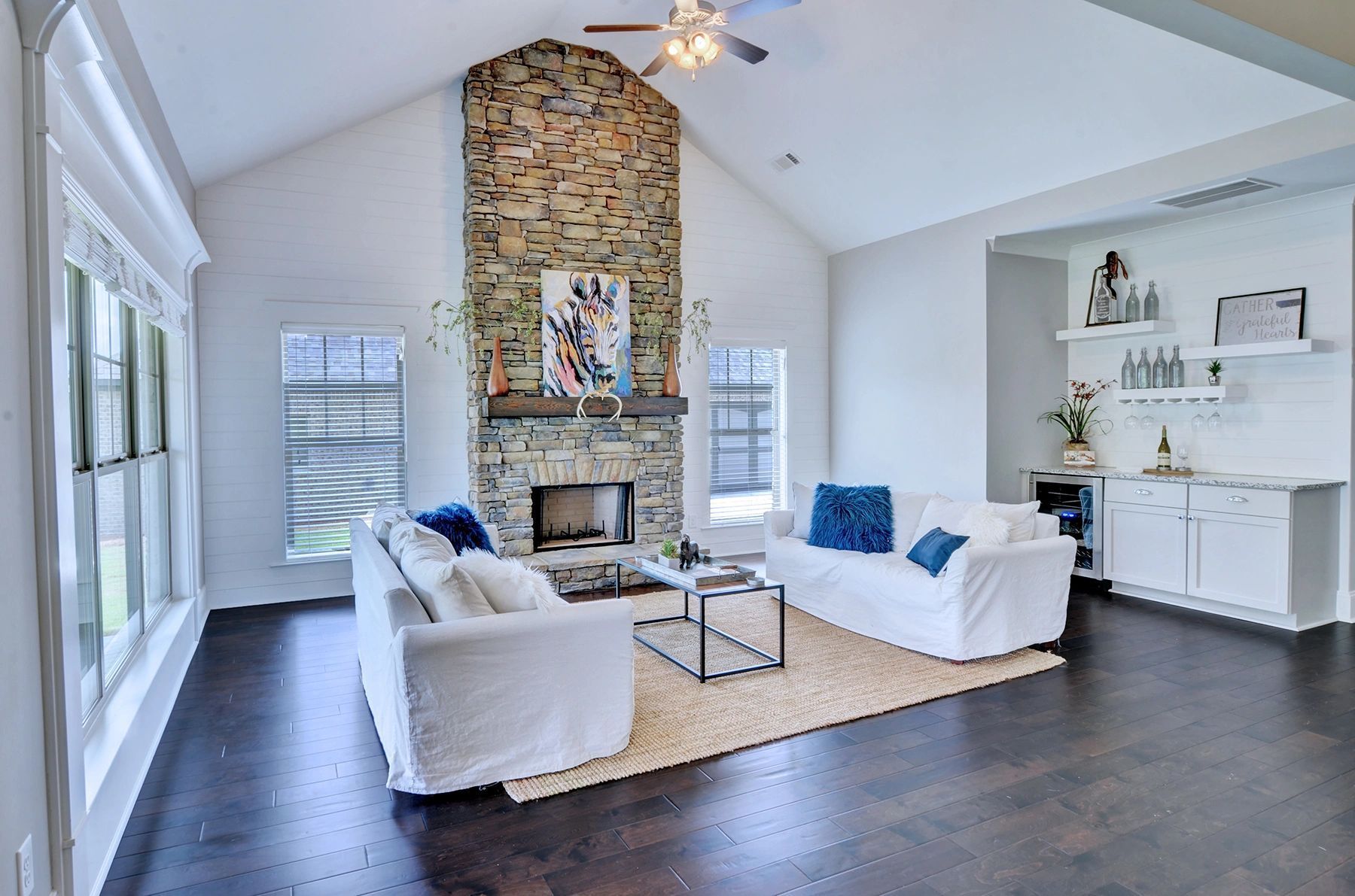 A living room with two couches , a fireplace and a ceiling fan.