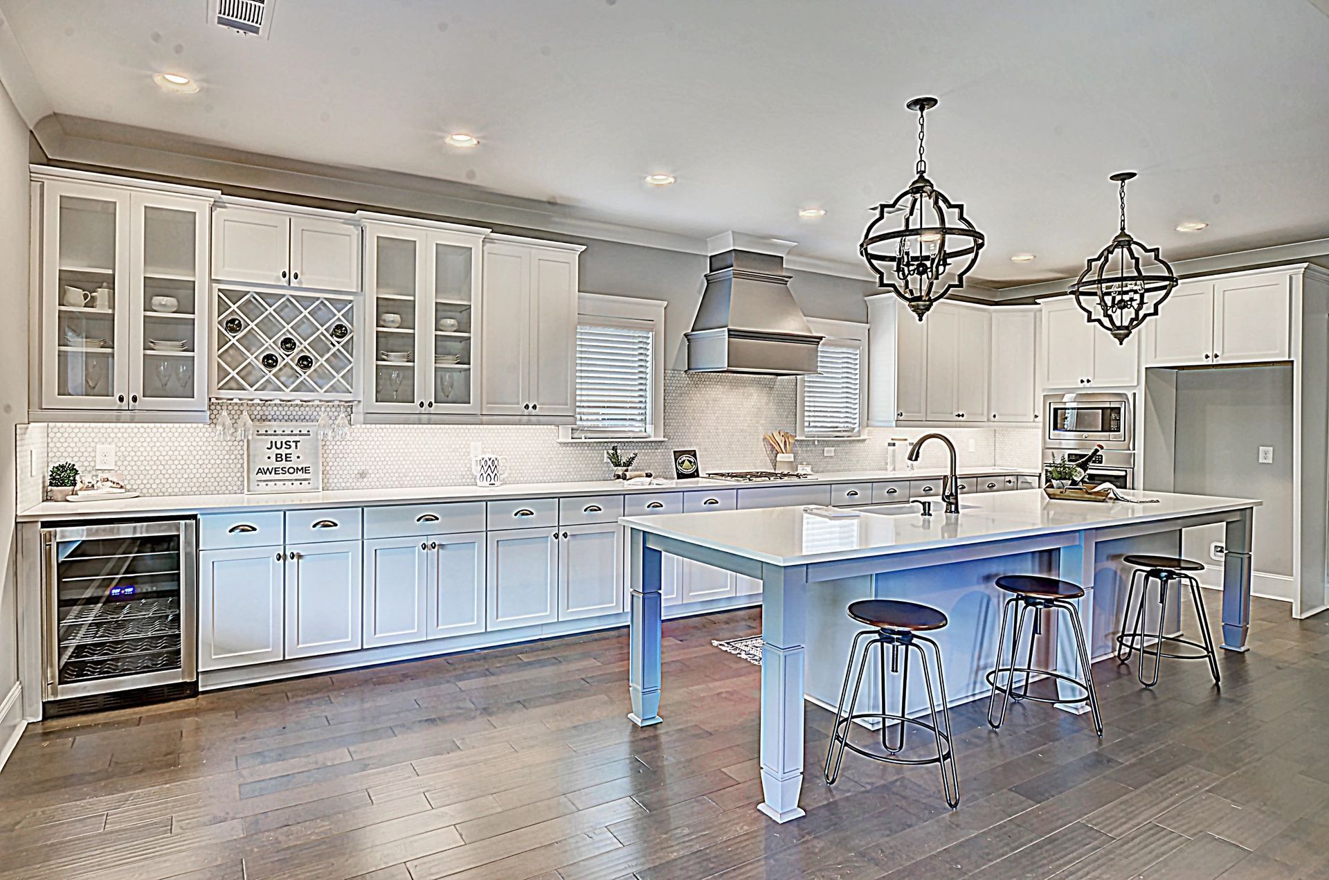 A large kitchen with white cabinets and a blue island.