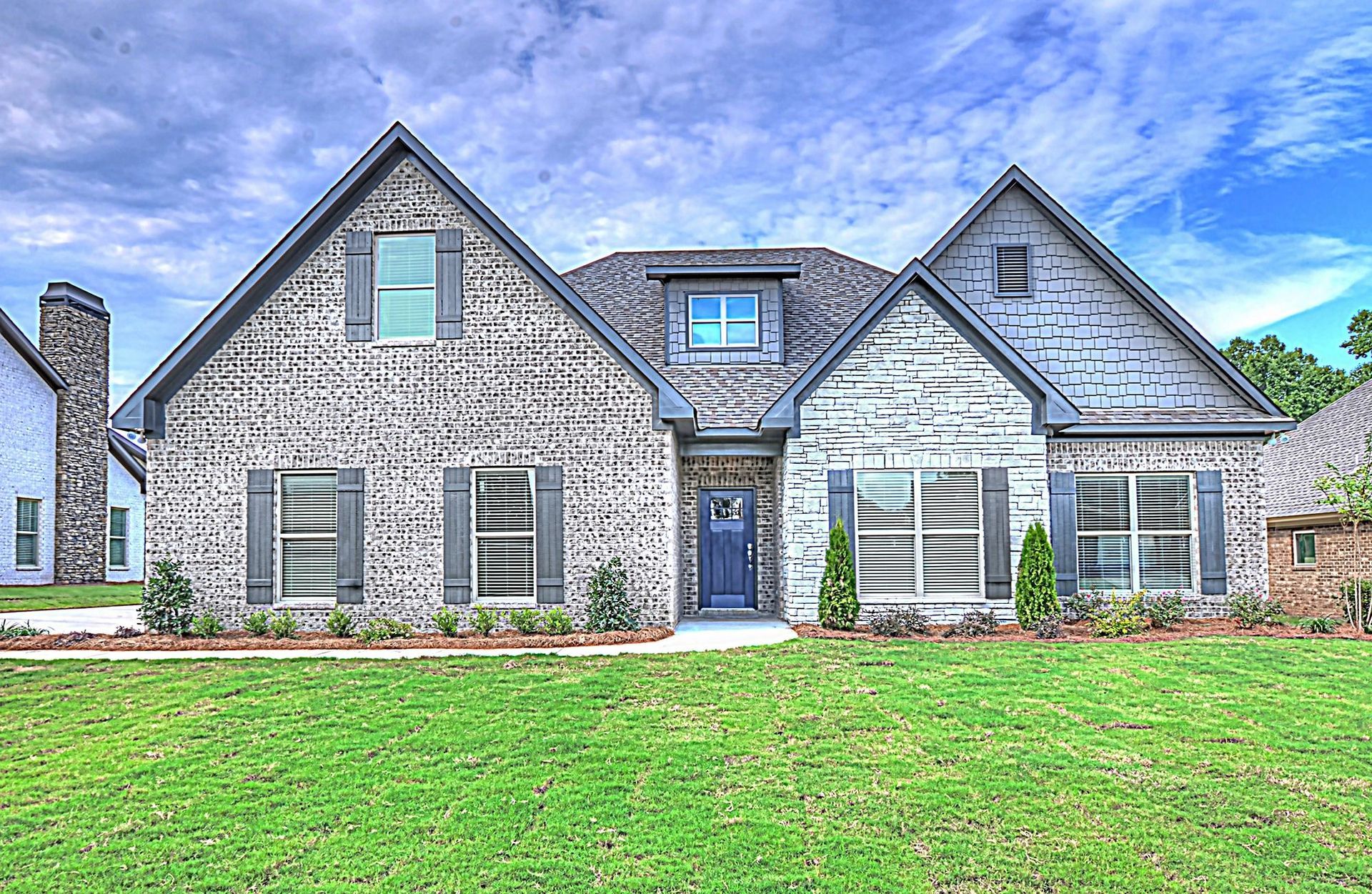 A large brick house with a large lawn in front of it.