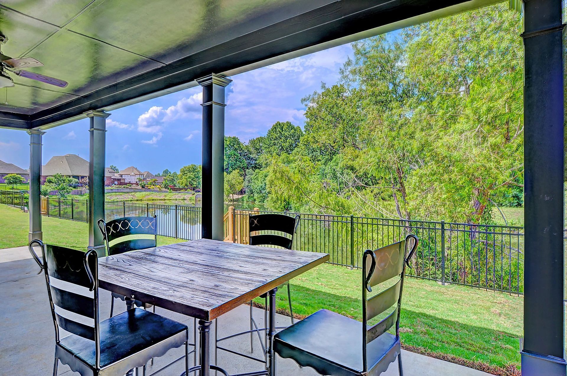 A patio with a table and chairs and a view of a lake.