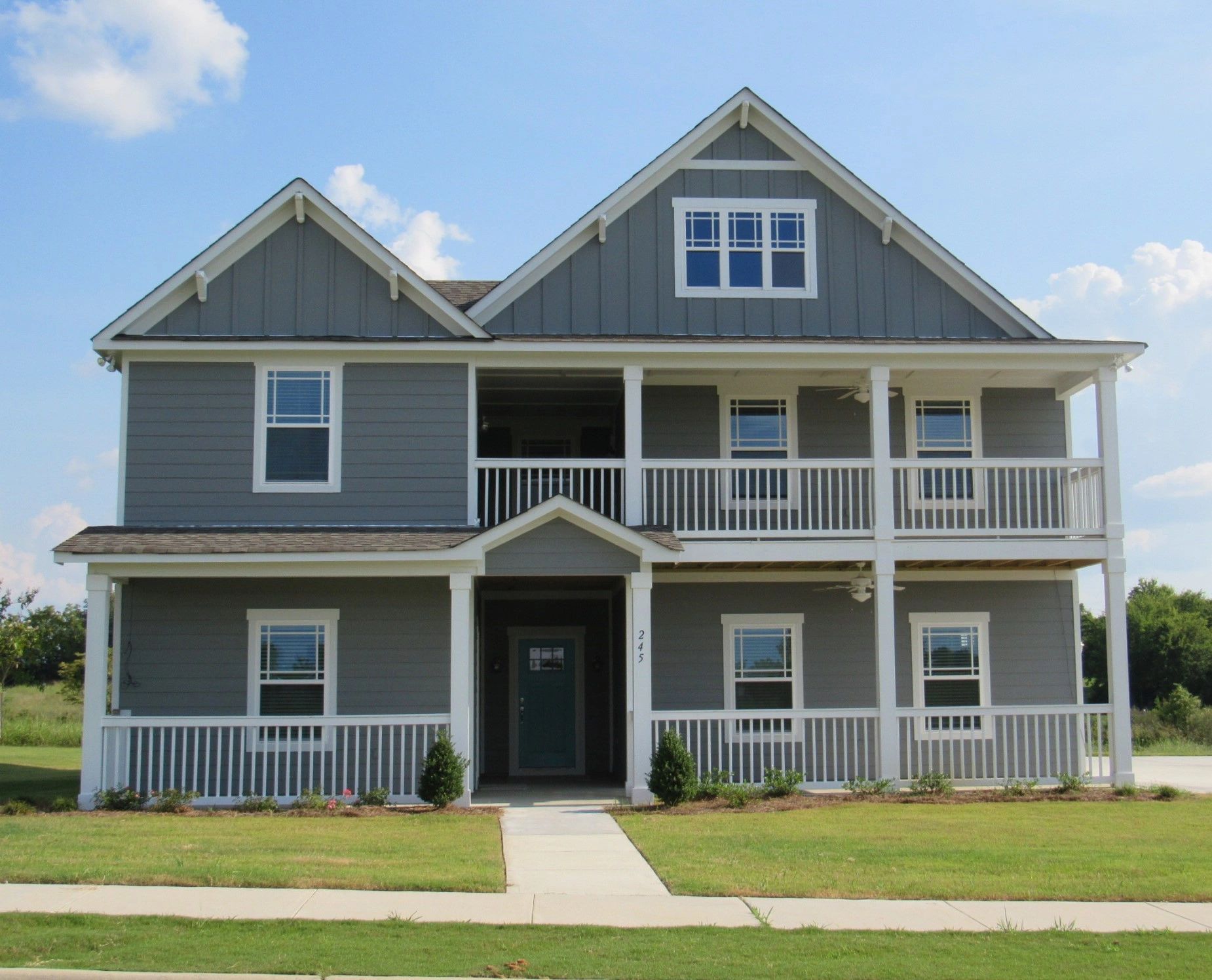 A large gray house with white trim and a blue door