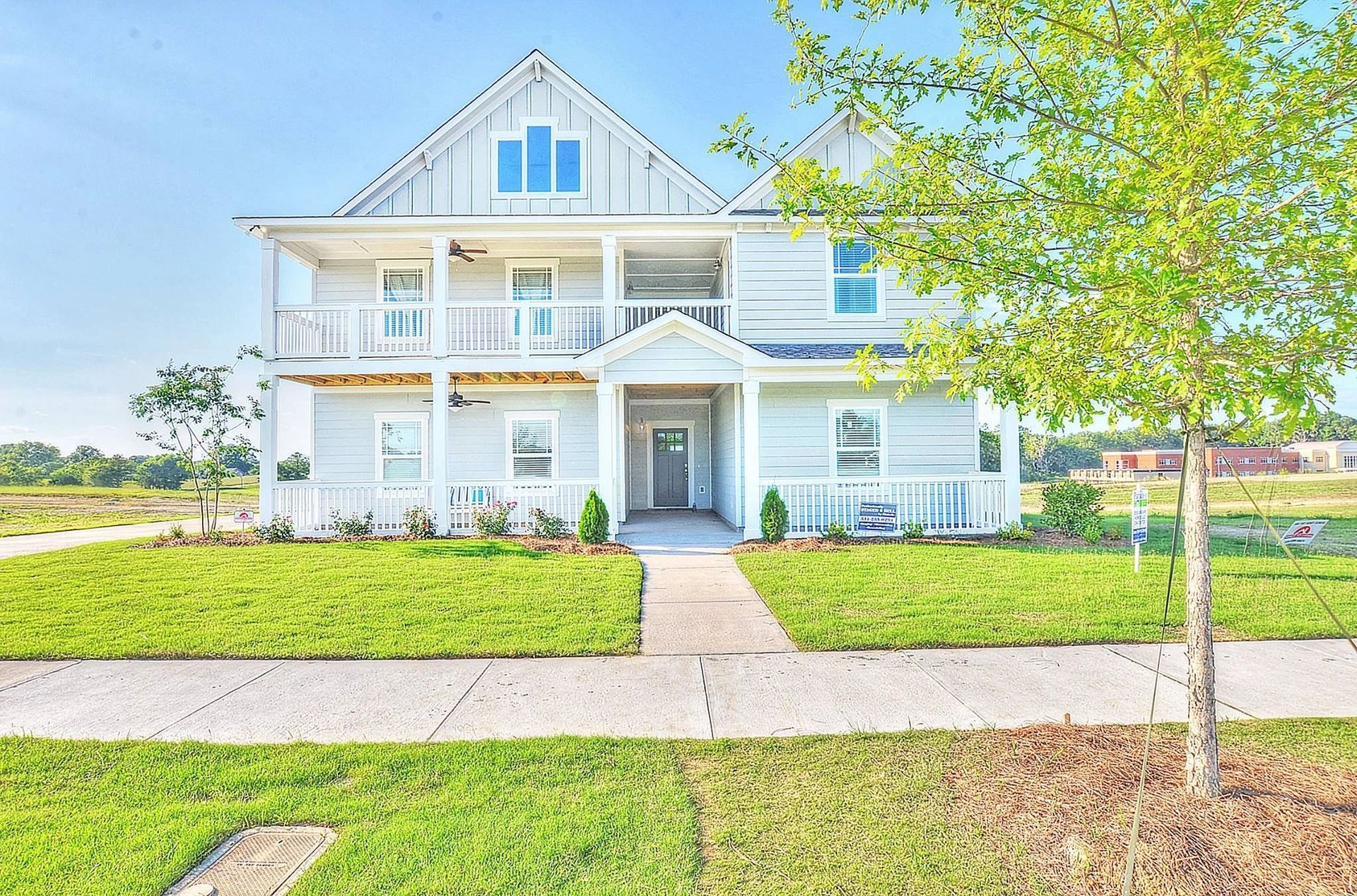 A large white house is sitting on top of a lush green field.