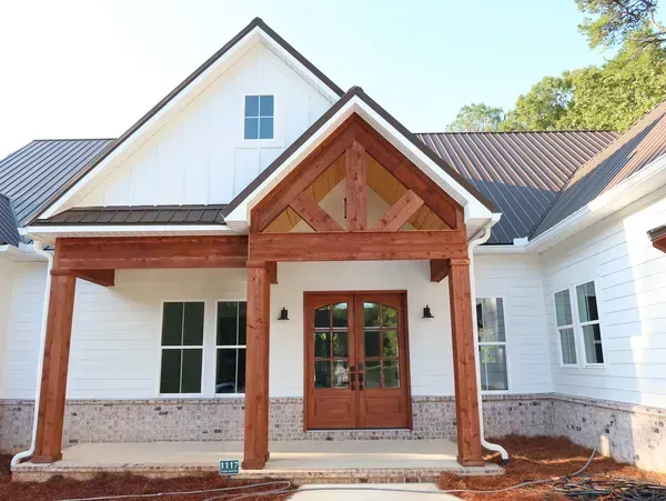 A white house with a wooden porch and a brown roof