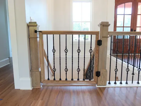 A wooden gate is attached to the railing of a staircase.
