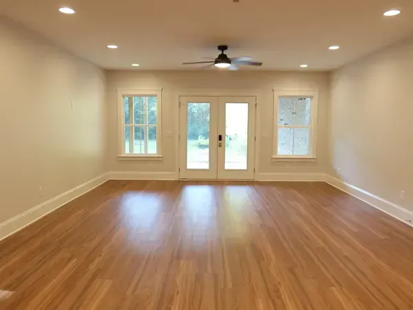 An empty living room with hardwood floors and a ceiling fan