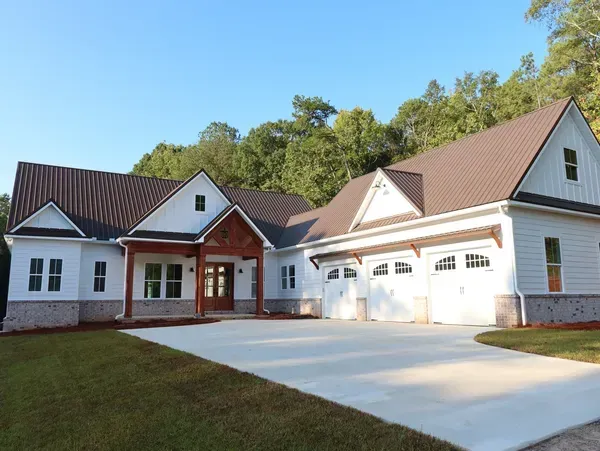 A large white house with a brown roof and a driveway