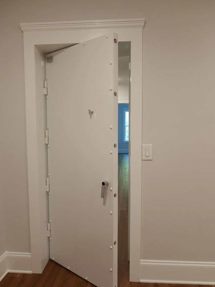 A white door is open in a room with a light switch on the wall.