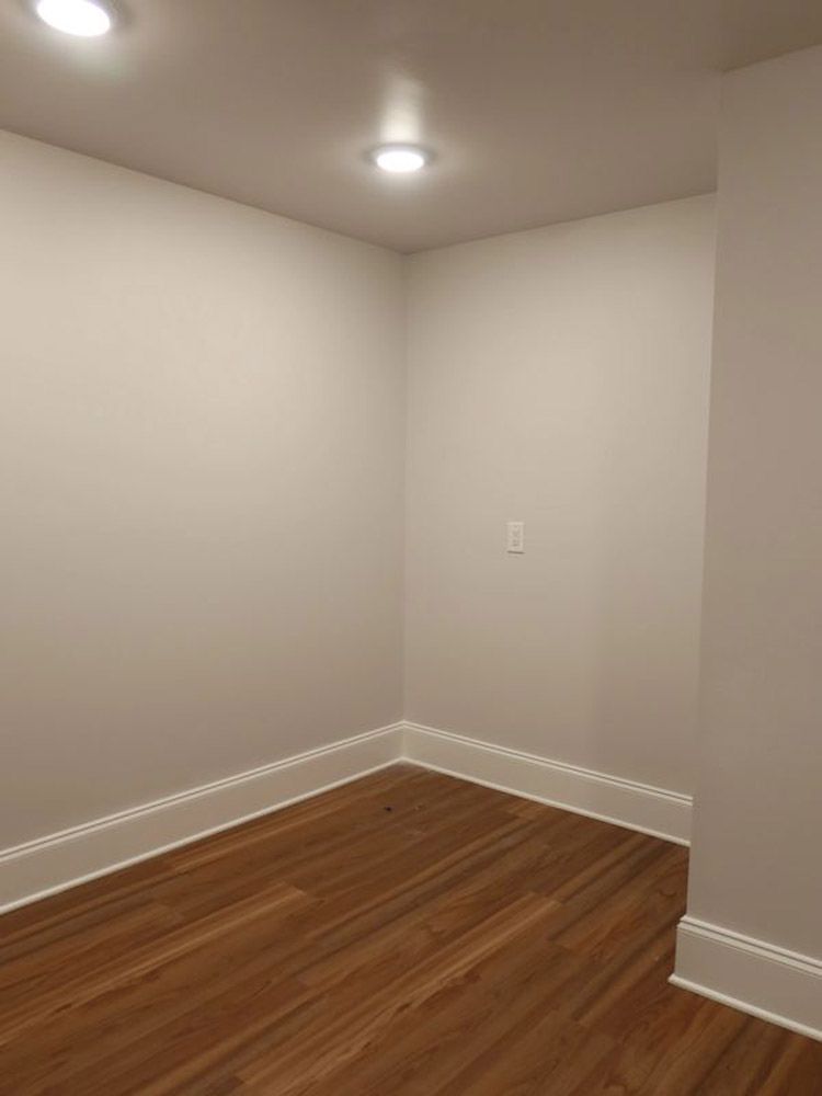 An empty room with hardwood floors and white walls.
