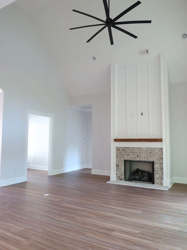 An empty living room with a fireplace and a ceiling fan.